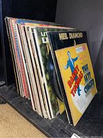 Side angle view of the vinyl records showing album covers and record edges.