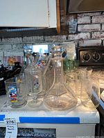 Full view of various clear glass decanters and bottles on kitchen counter.