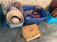 Overview of two totes filled with assorted hats, purses, and clutches, plus two canvas shoulder bags on the floor in front.