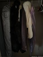 Multiple jackets hanging in closet including fur, leather, and cashmere items
