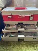 Closed and partially open view of the Plano toolbox showing three compartments with assorted jewelry making components organized in trays and plastic bags.