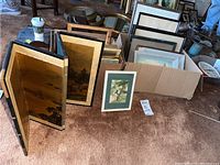 Wide shot featuring the folding screen and numerous framed sketches and prints stacked in a box and leaning on the ground.