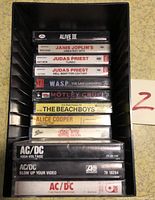 Photo shows the cassette tapes stacked inside a plastic tape case including AC/DC, Janis Joplin, Judas Priest, W.A.S.P., Motley Crue, The Beach Boys, Alice Cooper.