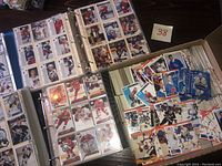 Four open binders laid out around a box of loose cards showing binder pages and box contents