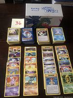 Top view of arranged Pokémon cards outside the box showing various Pokémon, Trainer, and Energy cards.