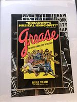 Framed Broadway Grease promotional poster showing colorful characters and text details, mounted over the framed NYC map.