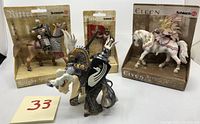 Schleich and Papo medieval fantasy figures and horses in packaging and one unboxed figure displayed, against white background