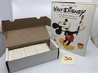Box with over 400 Walt Disney trading cards and the hardcover book "The Art of Walt Disney" showing front cover with Mickey Mouse painting.