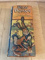 Front cover of vintage Bugs Bunny tall picture comic showing Bugs Bunny and other cartoon characters with a worn and damaged binding and edges.