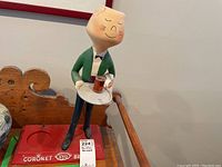 Full view of the Coronet Brandy butler serving figurine showing the figure holding a tray with a glass and standing on a red base with embossed logo.