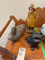 Photo showing vintage wood duck decoy, ceramic fisherman figurine, and ceramic dog figurine on wooden surface