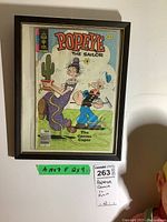Framed Popeye comic visible in wooden frame wrapped in plastic. The comic displays the cover titled 'The Cactus Caper' with a purple-dressed character and Popeye the Sailor.