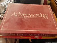 Maroon box of Adverteasing game showing the game title clearly on the lid.