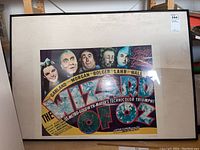 Full view of framed Wizard of Oz movie poster showing title and character portraits with mat and black frame