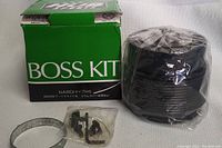 Photo of the unopened boss kit boxed in green packaging with included mounting hardware and clamp, kit wrapped in plastic.