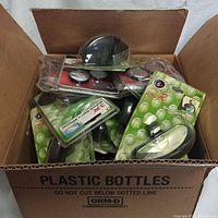 Open box containing multiple blind spot mirrors in sealed packaging, mostly green backing with various brands visible.