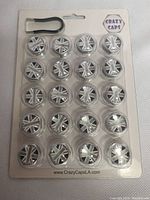 Front view of sealed blister card containing 20 silver Crazy Caps wheel covers with Union Jack design and attached removing tool.
