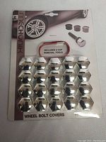 Photo of Mechunik chrome wheel bolt covers in factory packaging, includes 15 caps and removal tools, front view.