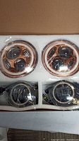 Two round LED projector headlights and two smaller round LED lights in foam packaging inside a box.