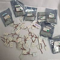 Photo showing multiple factory sealed anti-static bags containing LED auto lamp lights, some unpackaged lights laid out on white fabric background.