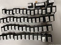 67 black rectangular Mack time delay modules arranged in rows showing front labels and electrical prongs.