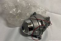 Close-up of one halogen low beam lens projector light showing metal housing, glass lens and attached wiring