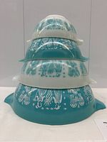 Stack of four Pyrex mixing bowls alternating turquoise and white exteriors, showing overall set and pattern alignment