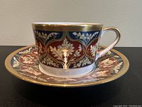 Full view of the cup on its matching saucer showing the detailed Tabriz floral and gold pattern.