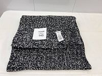 Folded black and white knit scarf showing texture and size.