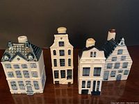 Front view of four Delft houses showing detailed windows, doors, and chimney tops.
