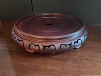 Front and top view of the rosewood carved round stand showing polished wood surface and central hole.