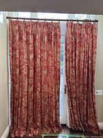 Full view of two linen drapery panels on curtain rod over glass door, showing fabric pattern and pleats.