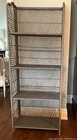 Front view of the wicker shelving unit showing all 5 shelves and lattice weaving pattern with curved side posts.