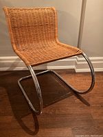 Photo showing front and side angle of chair with woven rattan seat and backrest mounted on chrome cantilever frame.