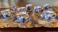 Eight demitasse cups and saucers on a silver tray, front angle