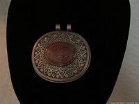 Front view of vintage Middle Eastern silver pendant with carved red stone and Arabic writing, set against black background.
