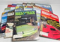 Photo showing multiple Road & Track magazines stacked with various colorful cover images of cars including Corvette Camaro and others