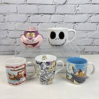 Front view of 5 Disney mugs featuring Cheshire Cat, Jack Skellington, Tigger, Muppets, and Lion King.