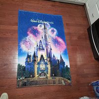 Full view of the Disney World Cinderella Castle throw blanket laid flat on a wooden floor, showing vibrant fireworks, castle, and Walt Disney World logo.