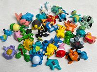 Top view showing an assortment of 35 colorful Pokémon PVC figurines arranged loosely on a white surface.