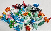 Top-down view of all 35 Pokemon PVC figures scattered on a white surface showing various characters including Charmander, Groudon, and others.