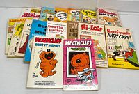 Image of 15 vintage cartoon comic strip paperback books arranged fanned out showing colorful illustrated cover art of various characters.