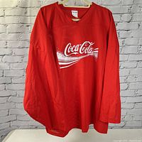 Front view of red Coca Cola jersey with white logo and V neckline