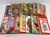 View of all 15 vintage pulp detective mystery paperback books arranged upright showing spines and some cover art.