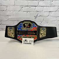 Front view of the toy wrestling belt showing full details of the central plate with WWE logo, American flag colors, and side plates with gold star designs.