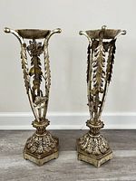 Front and angled view of both vintage metal candle holders, showing leaf and rose decorative detailing and hexagonal bases.