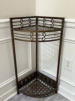 Front side view of bronze metal corner shelf showing front and side metal bars and decorative scrollwork on top tier