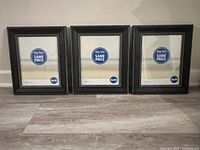 Three black 8x10 frames lined up on floor against wall showing front view with placeholder paper inside.