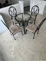 Full view of dining table with all four matching metal chairs around it in a tiled room.