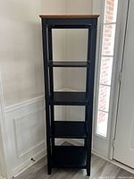 Front view of 5-tier shelf display rack showing all five shelves and brown top. Black frame with visible minor scratches on shelves.